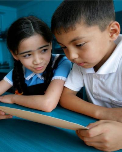 A boy and a girl sitting in a classroom and reading together